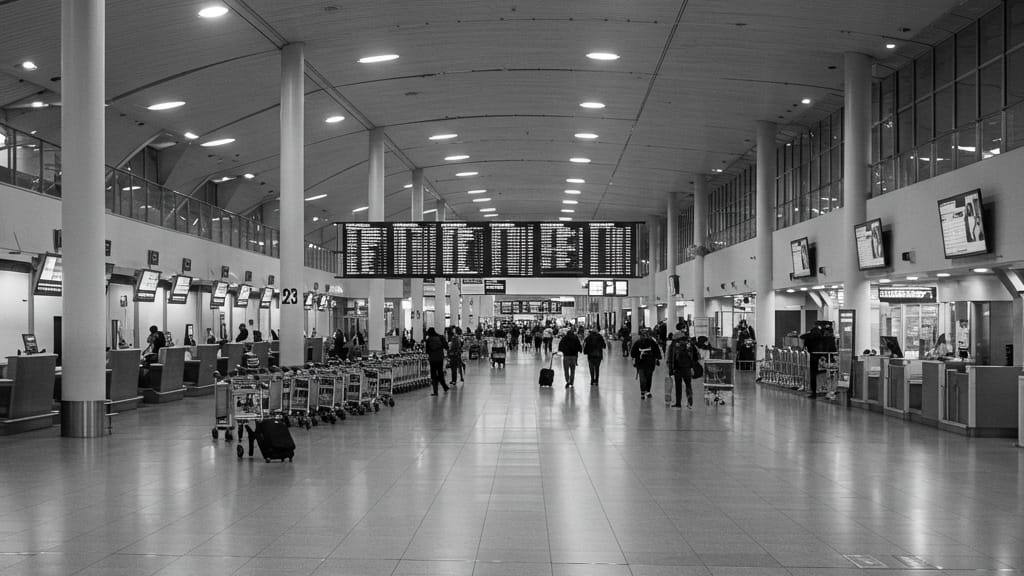 Travelers walking through an airport terminal beneath a departures board